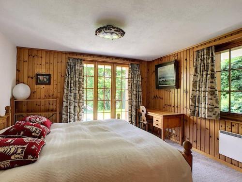 a bedroom with a bed and a desk and windows at Chalet Lion d'Or in Bagnes