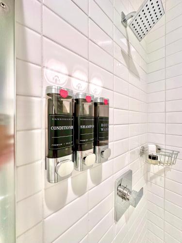 a white tiled bathroom with four bottles of lipstick at Modern Desert Retreat, Heated Pool, Firepit, Minutes to Coachella in Palm Springs