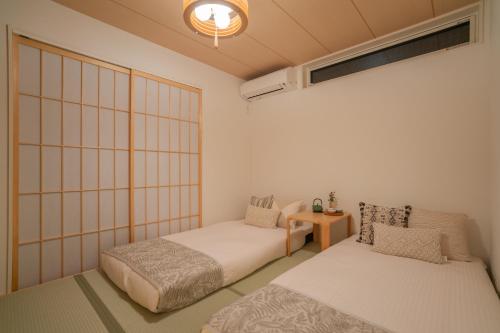 a room with two beds and a table in it at 京都清水五条 Maison Le Rouge燕脂 in Kyoto