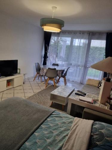 a living room with a bed and a couch and a table at Appartement de 51 m2 avec jardin de 51 m2, parking privé in Achères