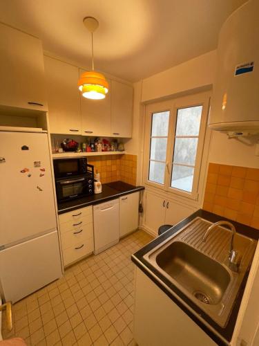 une cuisine avec un évier et un réfrigérateur dans l'établissement Charming and bright flat in a very convenient area, à Paris