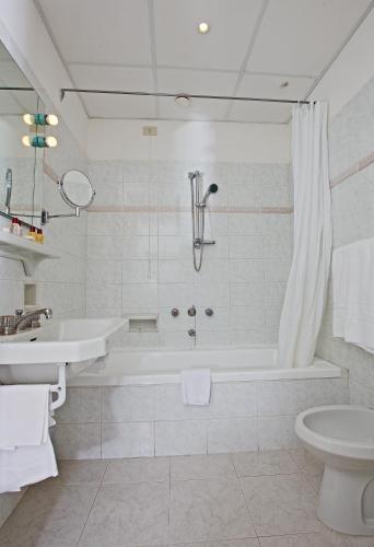 a white bathroom with a tub and a sink at Hotel San Michele in Anacapri