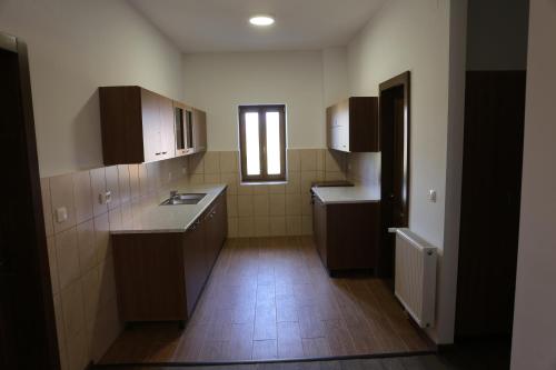 a small kitchen with brown cabinets and a window at Ezüstfenyő Agroturisztikai Panzió in Borzont