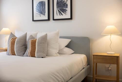a bedroom with a bed with white pillows and two lamps at Stylish 4-Bed Waterfront Home with Private Pool in Maroochydore