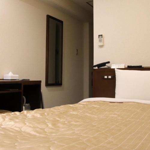 a bedroom with a bed and a desk and a mirror at サンホテル尼崎 in Amagasaki