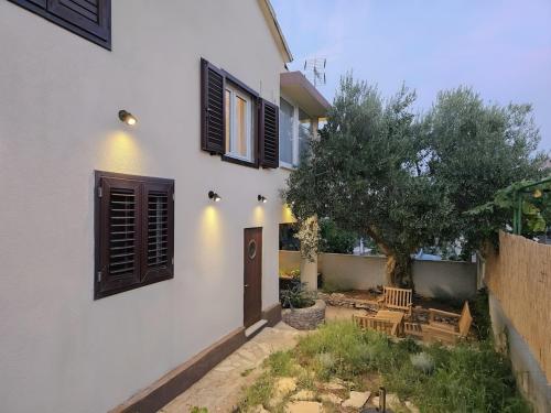 a white house with a door and a tree at Grandma's house in Rogoznica
