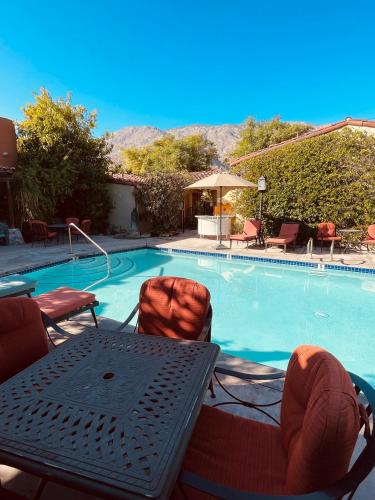 a swimming pool with a table and chairs next to it at Los Arboles Hotel in Palm Springs