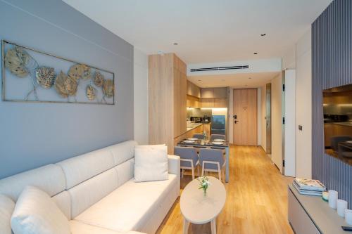 a living room with a white couch and a kitchen at La Green Hotel and Residence in Bang Tao Beach