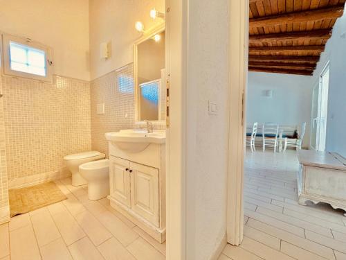 a bathroom with a toilet and a sink and a mirror at Villetta i Pini in Baja Sardinia