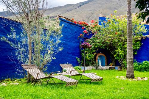 two chairs and a tree in a yard with a blue building at Apartamento QUIRA 2 in Villa de Leyva