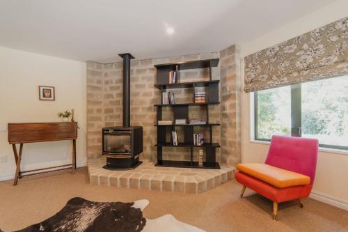 a living room with a fireplace and a chair at 1BR Retreat Self-Contained & Private - Waitaki in Lake Tekapo