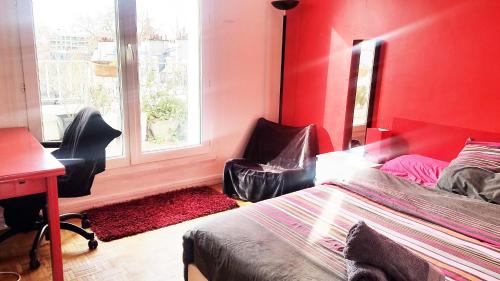 Cette chambre rouge comprend un lit, un bureau et une fenêtre. dans l'établissement Top Floor Apartment & Terrace with View, à Paris