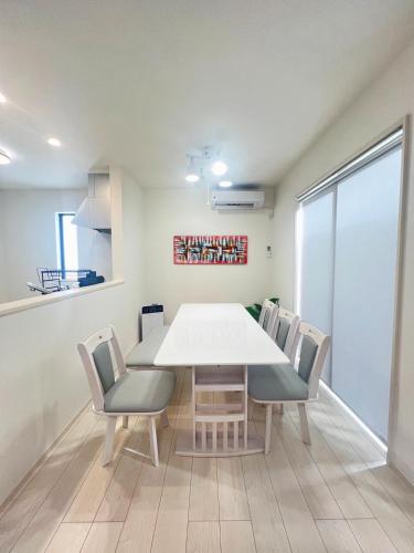 a dining room with a white table and chairs at vacation house N in Nago