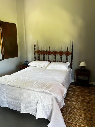 a bedroom with a large bed with white sheets at Fazenda Raiz da Serra in Itaguaí