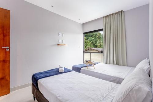 two beds in a room with a window at Casa em Paraty com 4 Suítes, Piscina e Churrasqueira Próximo Praias in Paraty
