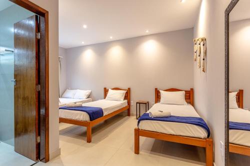 a room with two beds and a mirror at Casa em Paraty com 4 Suítes, Piscina e Churrasqueira Próximo Praias in Paraty