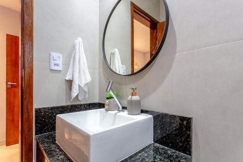 a bathroom with a white sink and a mirror at Casa em Paraty com 4 Suítes, Piscina e Churrasqueira Próximo Praias in Paraty
