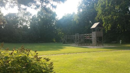 a playground in a field with a wooden structure at Hotel Restaurant Teichaue in Adendorf