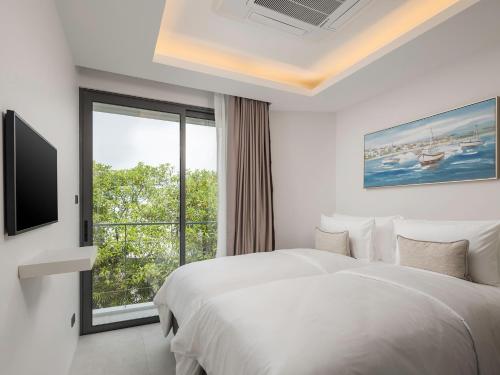 a hotel room with a bed and a window at Surin Seaview Villa by Elite Havens in Surin Beach