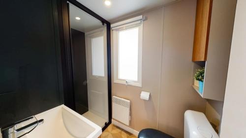 bagno con vasca, servizi igienici e finestra di Camping Le Marisol 5 étoiles Torreilles Plage a Torreilles