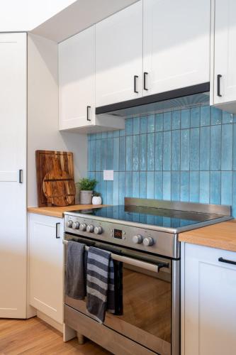 a kitchen with white cabinets and a stove top oven at Newcastle Escape 4-Bedroom House in Hamilton