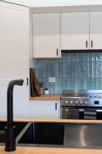 a kitchen with white cabinets and a stove at Newcastle Escape 4-Bedroom House in Hamilton