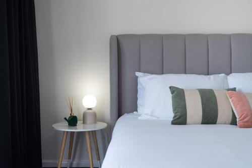 a bedroom with a bed and a table with a lamp at Newcastle Escape 4-Bedroom House in Hamilton