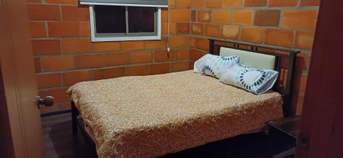 ein Schlafzimmer mit einem Bett mit einer Ziegelwand in der Unterkunft Casa de Campo con mirador in Cuenca
