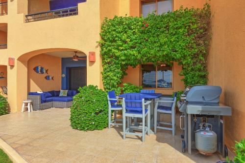 a patio with blue chairs and a table in front of a building at Right on the Beach! Ground Floor Princesa E104 in Puerto Peñasco