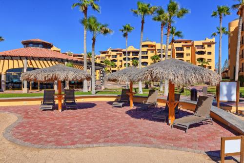 a group of chairs and tables with straw umbrellas at Right on the Beach! Ground Floor Princesa E104 in Puerto Peñasco