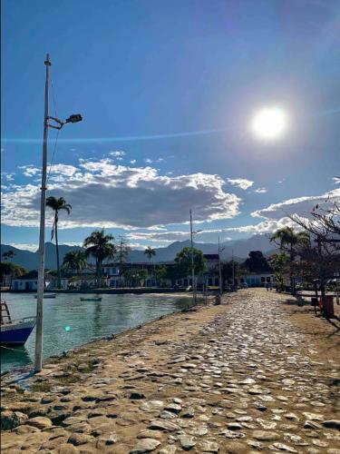 a road next to a body of water with palm trees at Casa em Paraty com 4 Suítes, Piscina e Churrasqueira Próximo Praias in Paraty