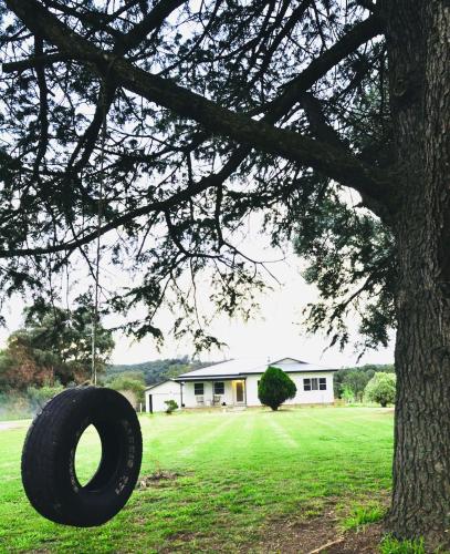 a tire hanging from a tree in front of a house at York Huon Farmhouse in Lower Botobolar