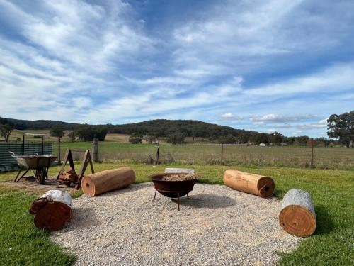 a group of wooden barrels and a grill in a field at York Huon Farmhouse in Lower Botobolar