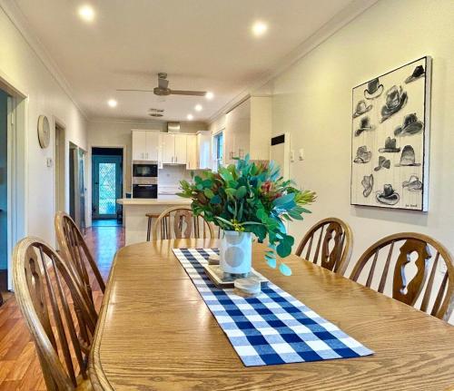 a dining room table with a vase of flowers on it at York Huon Farmhouse in Lower Botobolar