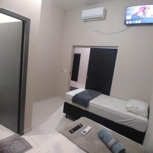a bedroom with a bed and a tv on a wall at Hotel America 2 in Tangara da Serra