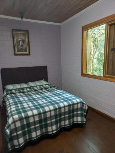 a bedroom with a bed with a checkered blanket at Cabana Aconchegante in São Francisco de Paula