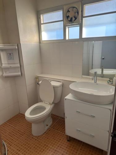a white bathroom with a toilet and a sink at NT House in Chiang Rai