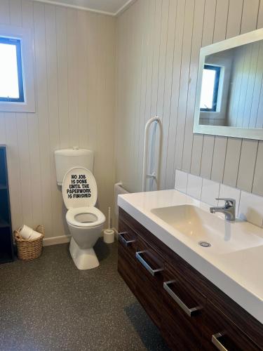 a bathroom with a toilet and a sink and a mirror at The Barnhouse Getaway in Roslyn Bush