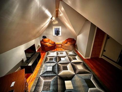 Cette chambre mansardée comprend un canapé et un tapis. dans l'établissement Stylish Detroit 3 bedroom 4 bed office bar, à Detroit