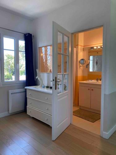 La salle de bains est pourvue d'un lavabo et d'une armoire avec un miroir. dans l'établissement Villa avec piscine chauffée, à Soulac-sur-Mer