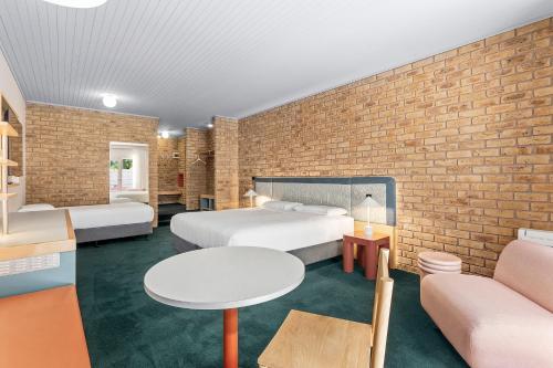 a hotel room with two beds and a brick wall at Motel Flinders in Flinders