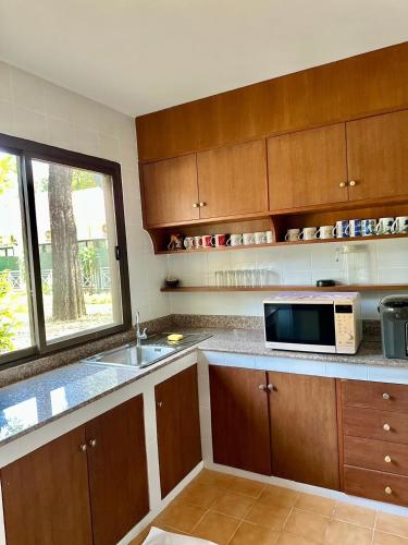 a kitchen with a sink and a microwave at Comsaed River Kwai Resort in Kanchanaburi