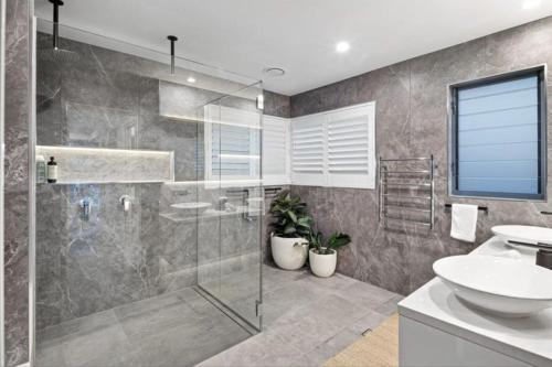 Un baño con ducha de cristal y lavabo. en Mimosa Lodge - 250m to Chinamans Beach in Jervis Bay!, en Hyams Beach