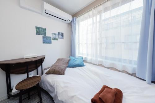 a bedroom with a bed and a desk and a window at Ra Grande by Tranova in Tokyo