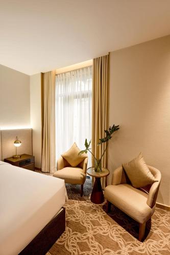 a hotel room with a bed and chairs and a window at REY Hotel Hanoi in Hanoi