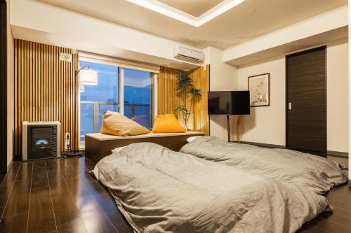 a bedroom with two beds and a large window at Cozy Stay Sapporo Hongodori 405 in Sapporo