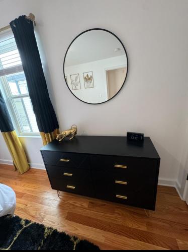 a black dresser with a mirror on a wall at Luxury Gated NYC Theme 3BR 2B with Parking by EWR in Elizabeth