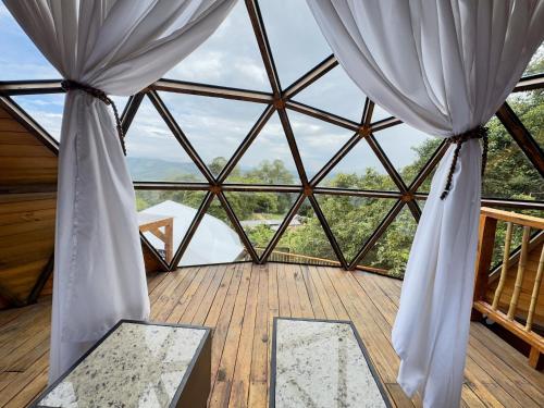 a large room with a large window with curtains at MACA GLAMPING in Calima