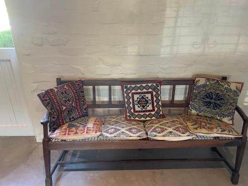 a bench with pillows on it in a room at Hartland Country House Luxury Double Rooms in Oudtshoorn