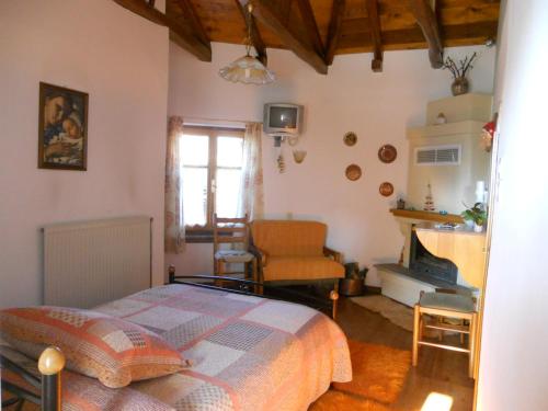 a bedroom with a bed and a chair and a fireplace at Sarafis Guesthouse in Agios Lavrentios